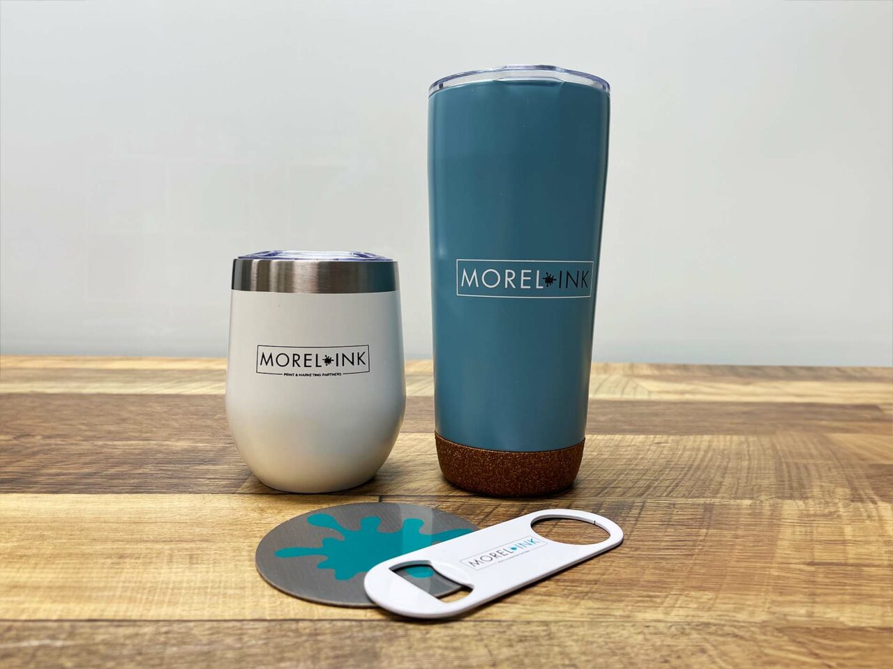 Example of Morel's promotional capabilities, showing custom branded tumblers, coaster, and bottle opener