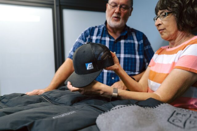 Two Morel team members showcase their apparel capabilities with a custom branded trucker hat
