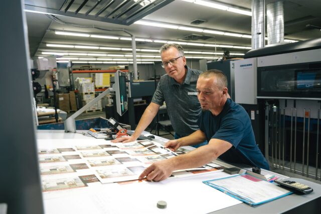 Two Morel team members do final presssheet review on a printed piece